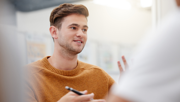 Zeigt einen jungen Mann mit einem Stift in der Hand.